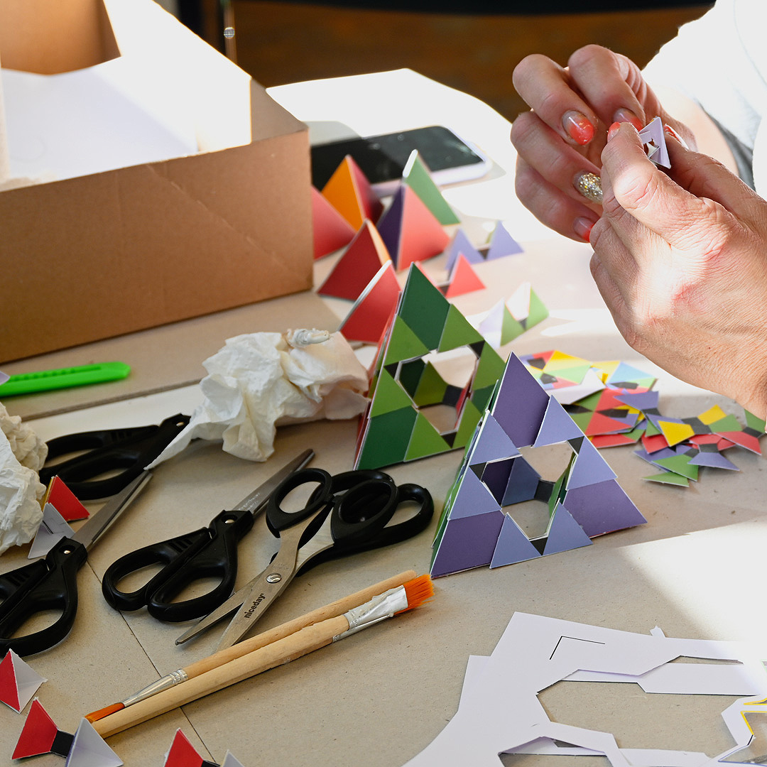 Interaktive Ausstellungsstation. Platonische Körper aus buntem Papier, Scheren und Stifte.